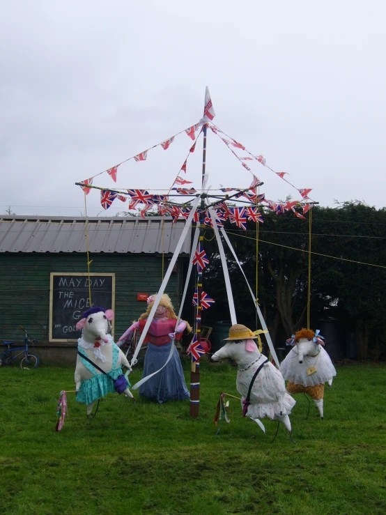 two cats in costumes standing in the grass with a carousel behind