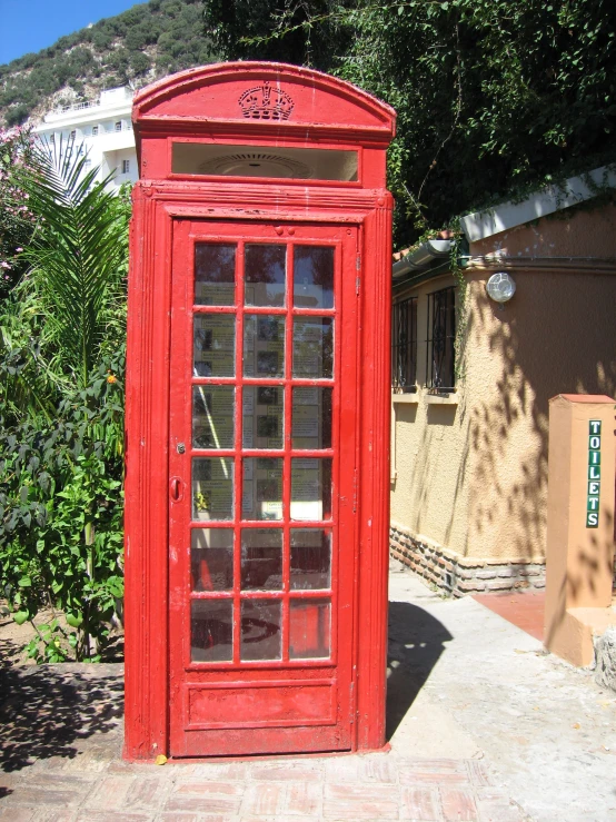 a red phone booth sitting in front of some trees