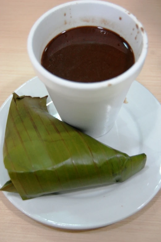 a cup of sauce and a piece of banana leaf