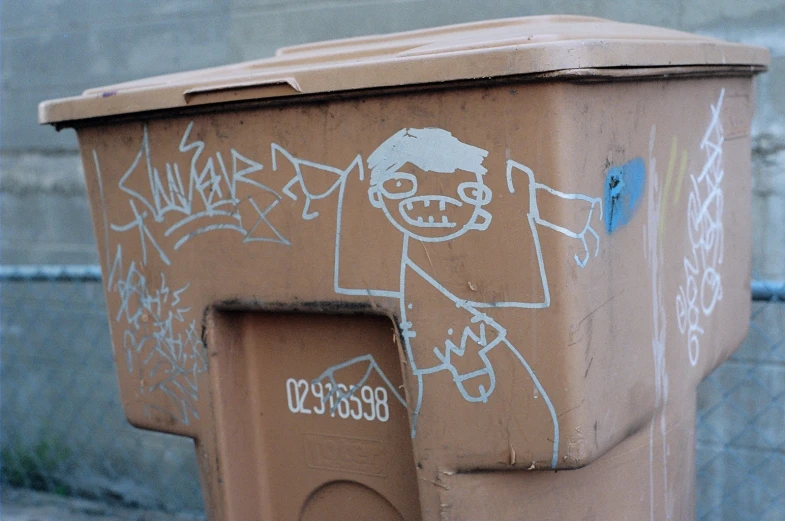 an artistic garbage can has been tagged with graffiti