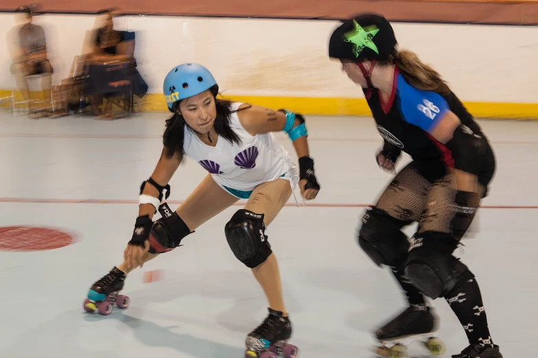 a couple of women on skateboards racing across a rink