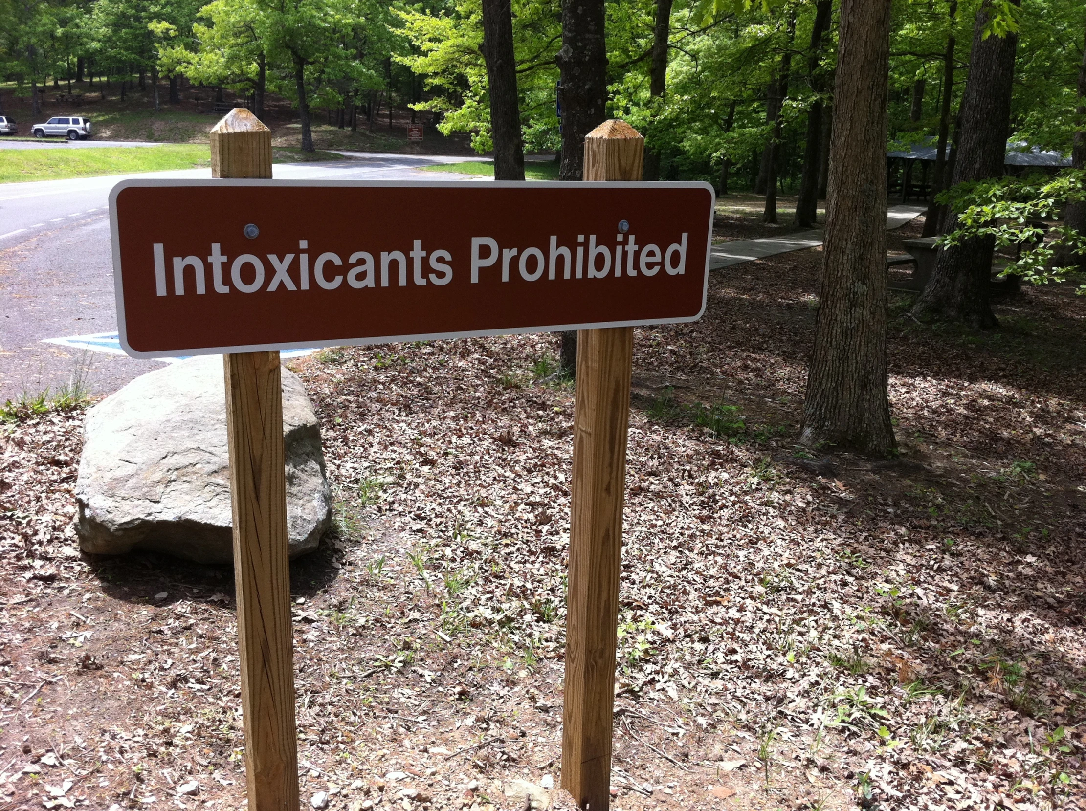 a sign saying intoxicated prohibited on a wooden post