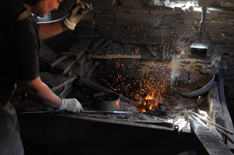 a man operating an old stove with some sort of fire in it