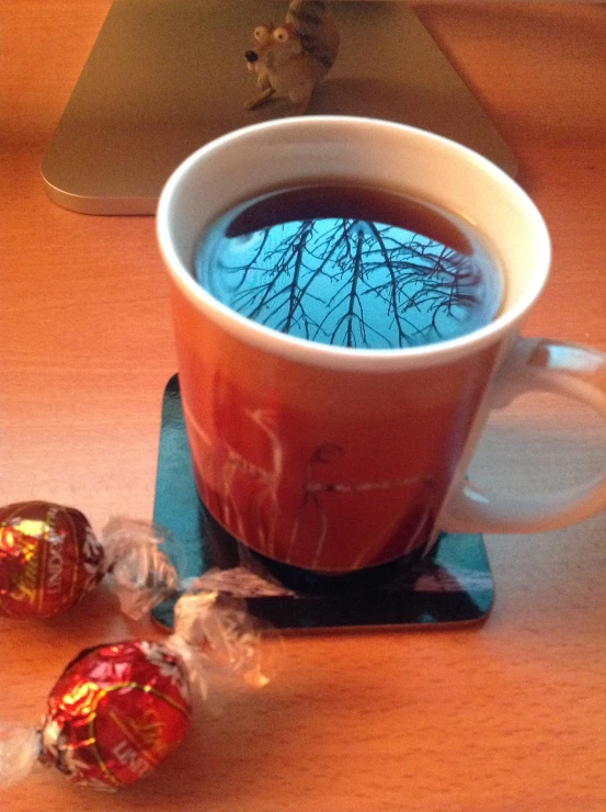 a cup of coffee sitting next to two candy