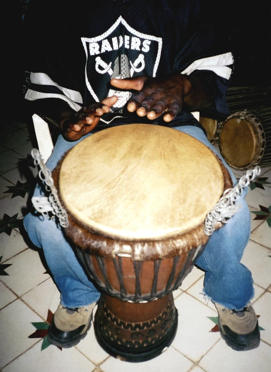 a man in black shirt sitting on a brown drum