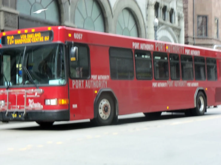 a red bus is parked in front of a building