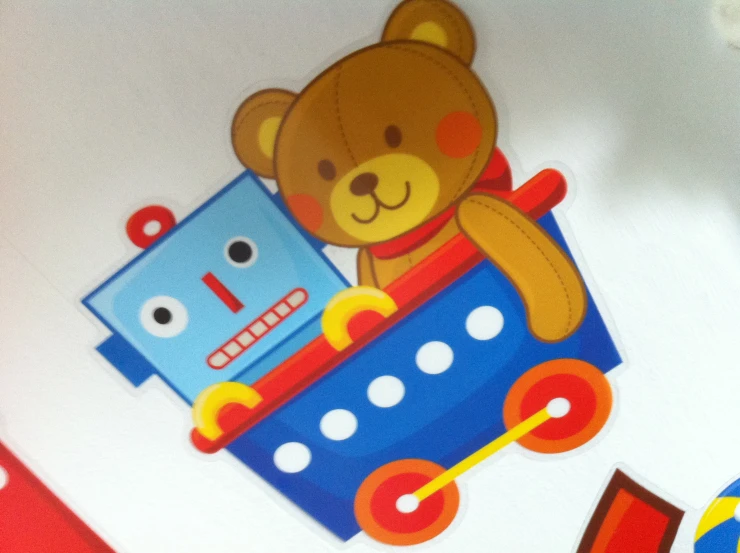 teddy bear in toy car on table with colorful wallpaper