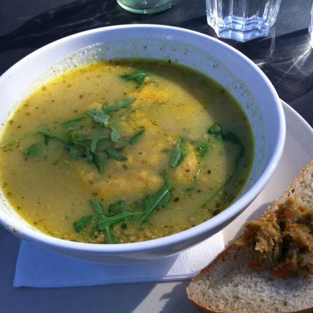 a white bowl filled with soup next to a slice of bread