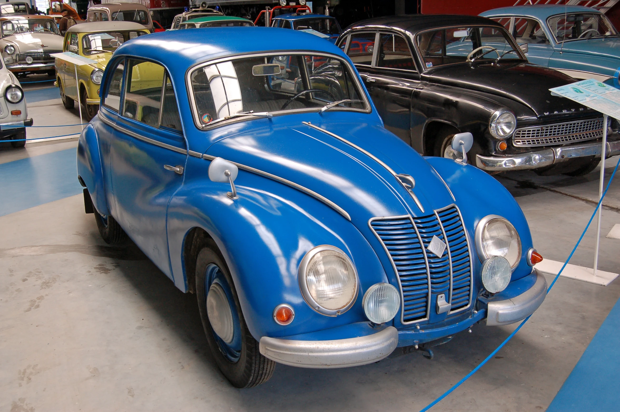 an old blue car is on display with other antique cars