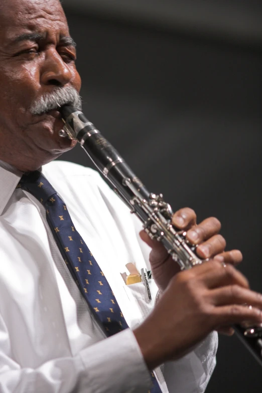 an older man playing the flute with other hands