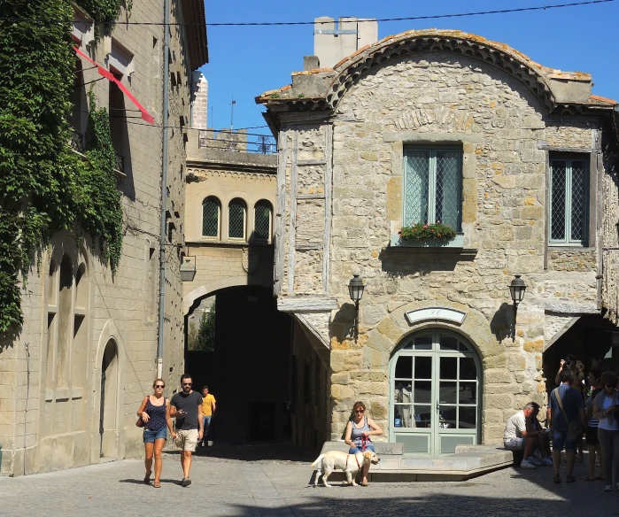 people walking through a stone arched courtyard near a building