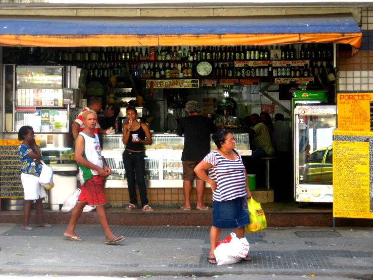 many people walking near a store with yellow awnings