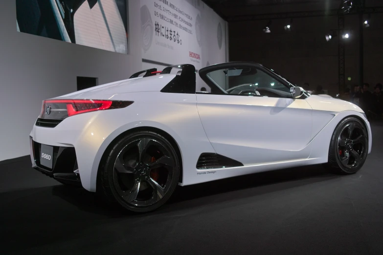 a white sports car with a roof down in a dark room