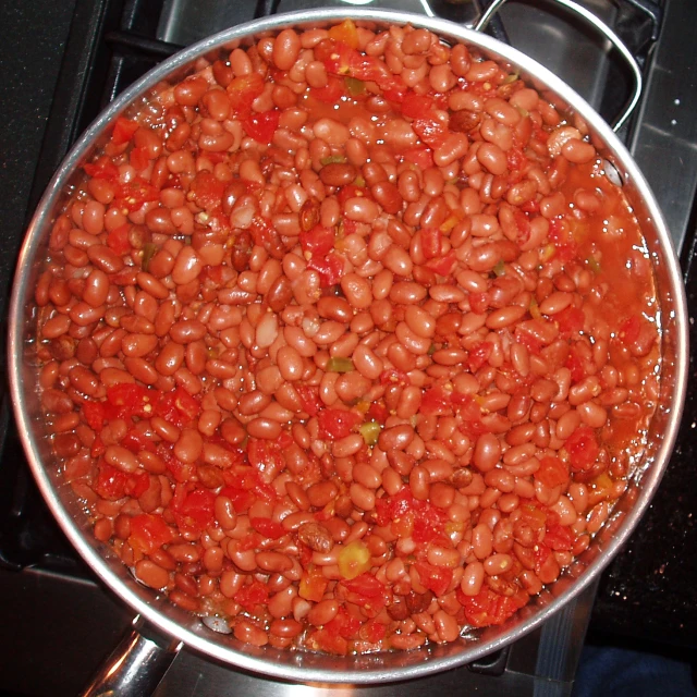 a pot filled with cooked beans sitting on a stove top