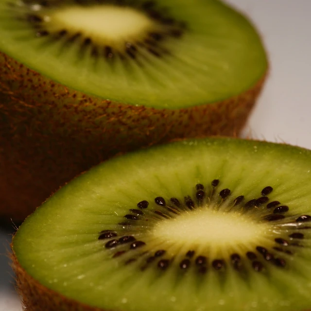 two kiwi cut into slices sitting on a table