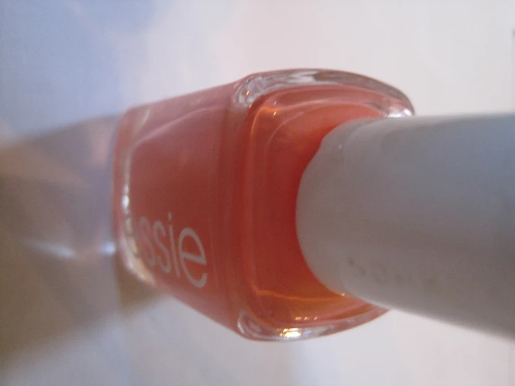 a small orange nail polish is seen in the picture