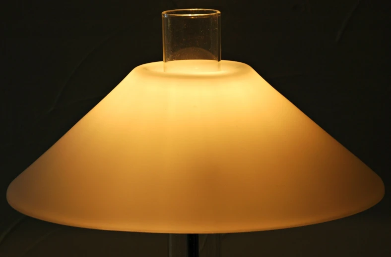 a glass and a base is sitting next to a lamp