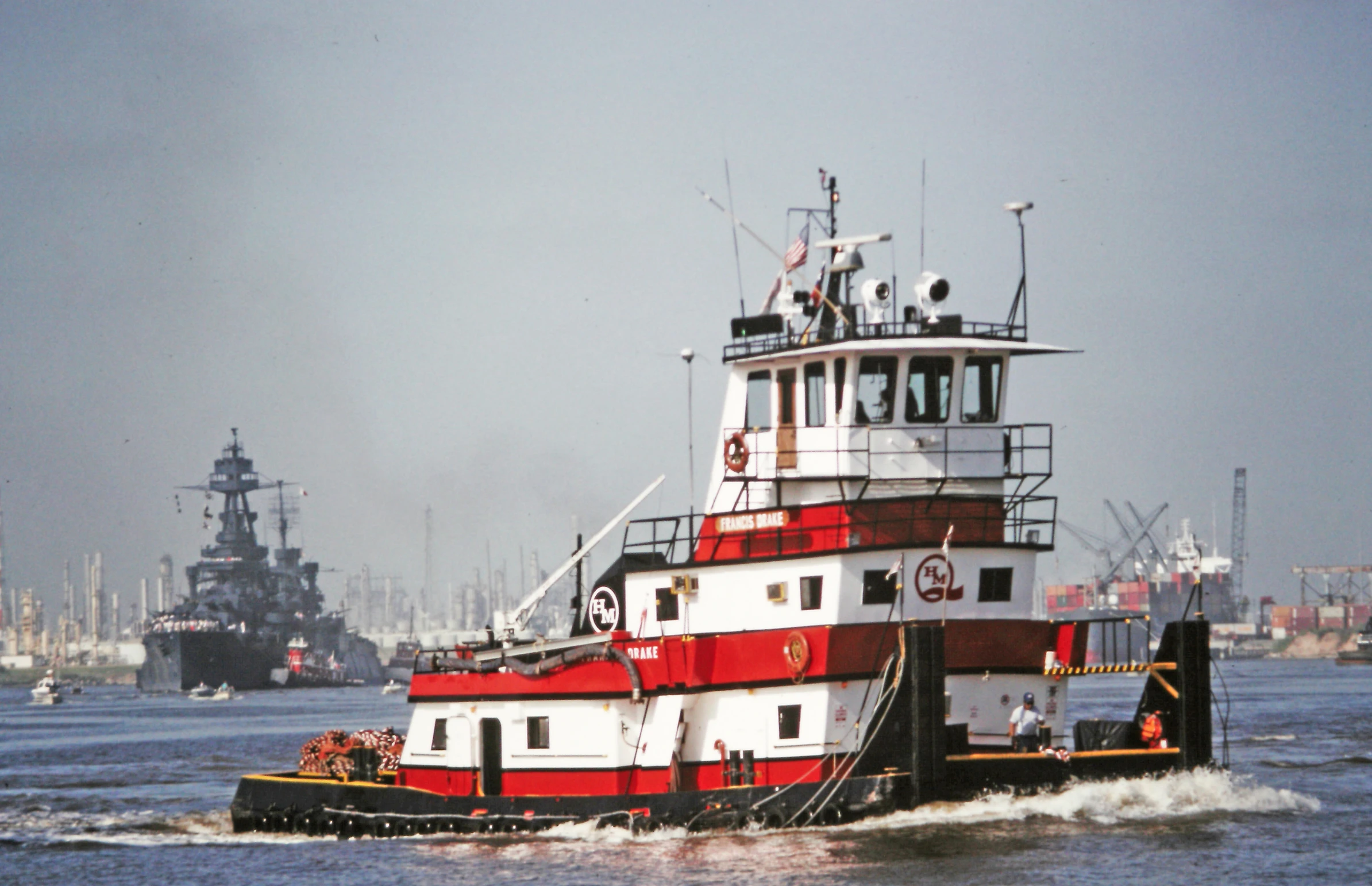 a tugboat sailing through the ocean next to other ships