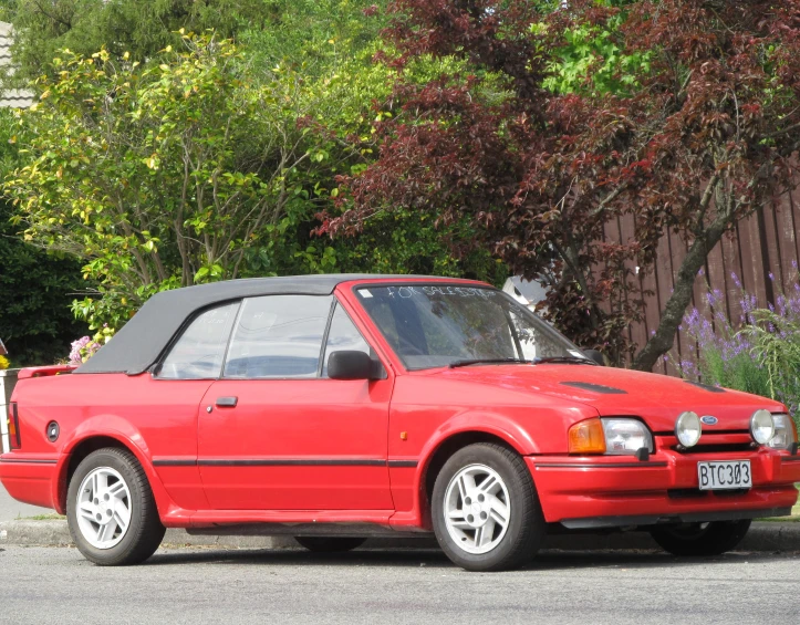 a red hatchback car is sitting on the street