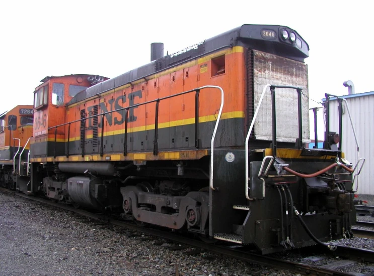 an orange train parked in front of an older building