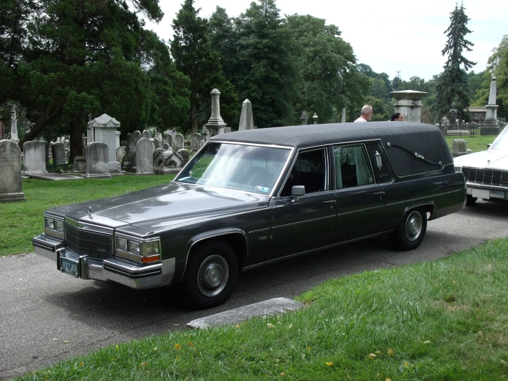 an old style limo parked near a headstone