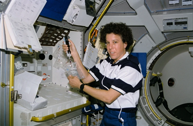 a woman in white and black uniform looking at some glass bottles