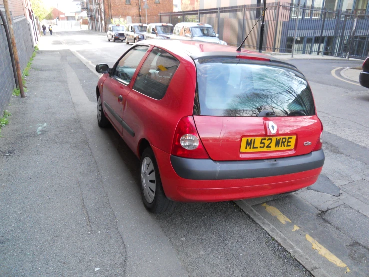 a red car sitting in a small parking space on the side of a street