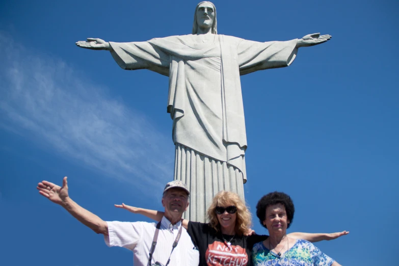 a group of three people pose with a statue