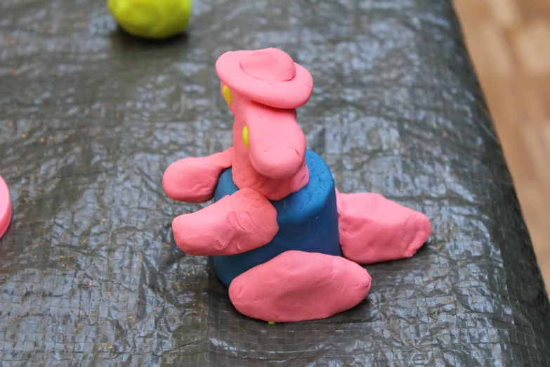 a play dough man sits on a table surrounded by toy tennis balls