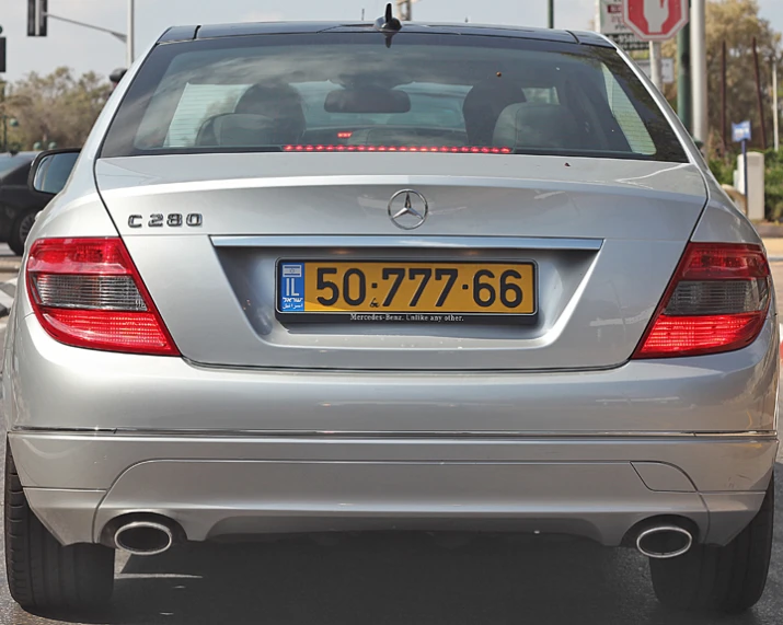 silver mercedes benz car stopped in traffic near the stop light