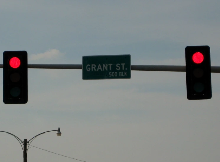 a traffic light and street sign hanging above a metal pole