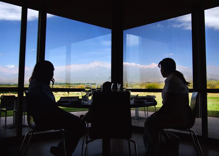 two people sitting at a table with some wine in the window