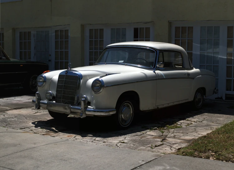 an old car parked on the sidewalk near some houses