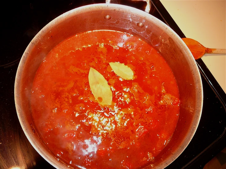 a red sauce cooking in a pot with spoons