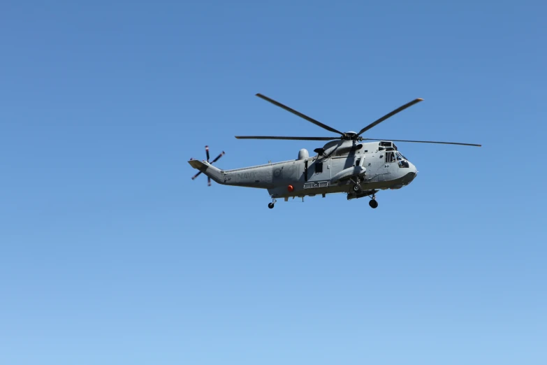 a large military helicopter flying through a blue sky