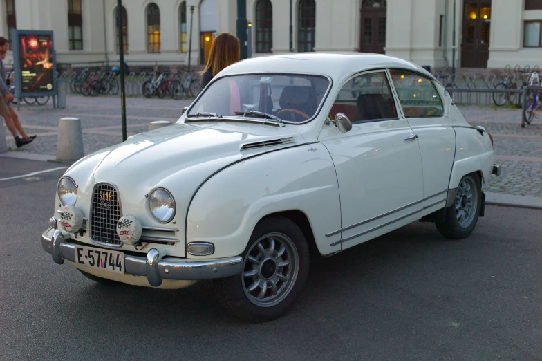 an old white car driving down the street