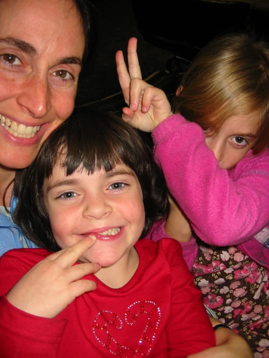 two children and an adult making the peace sign