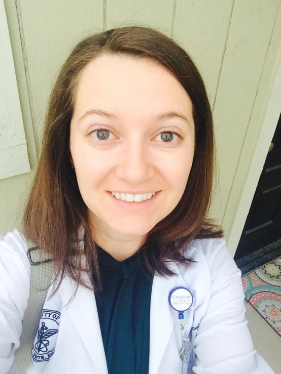 a smiling woman wearing a lab coat with a white jacket