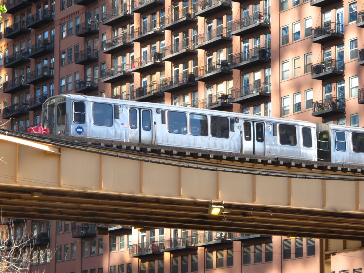 a long silver train is passing by several high rise buildings
