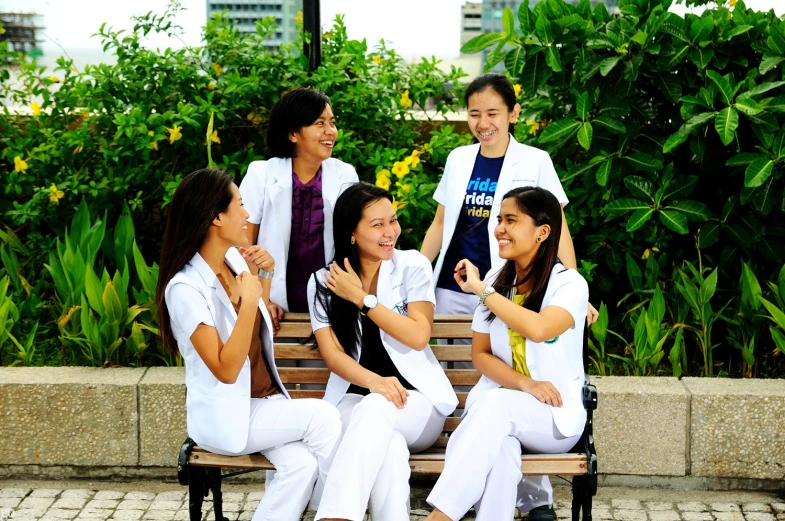 a group of young women sitting on top of a wooden bench