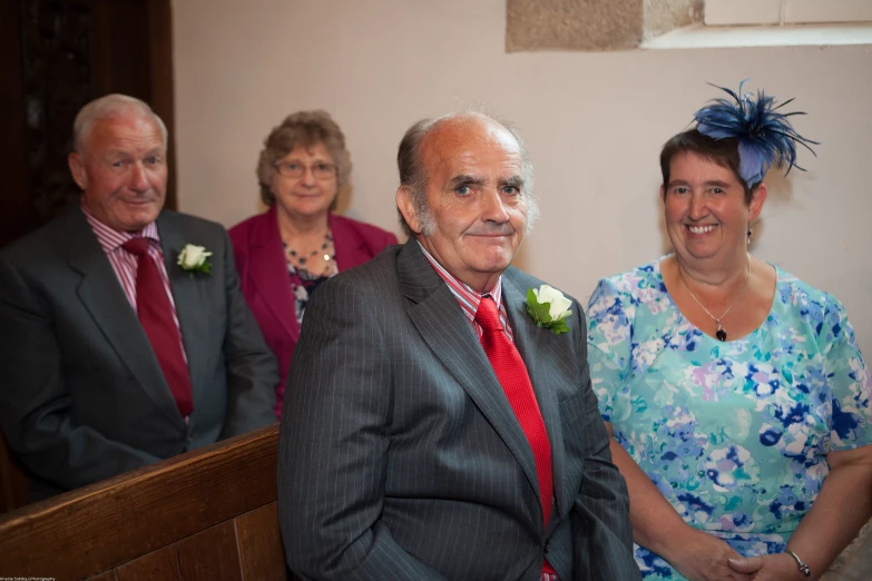 four people dressed in formal clothing smile together