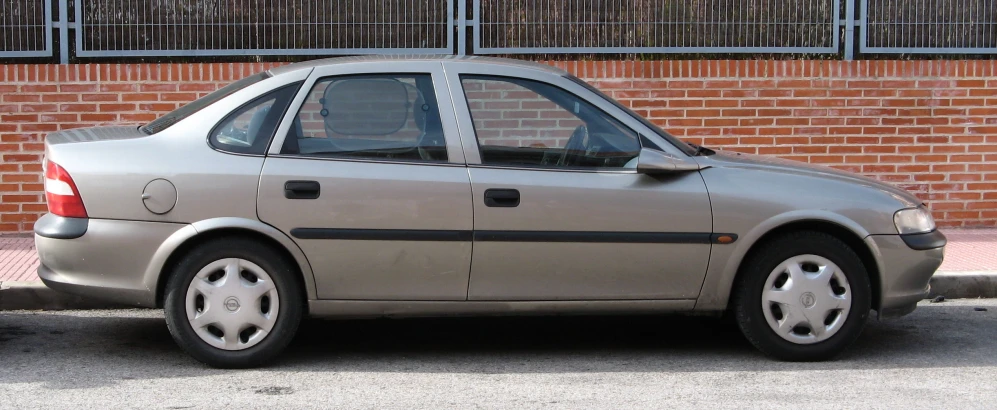 the grey car is parked near the brick wall