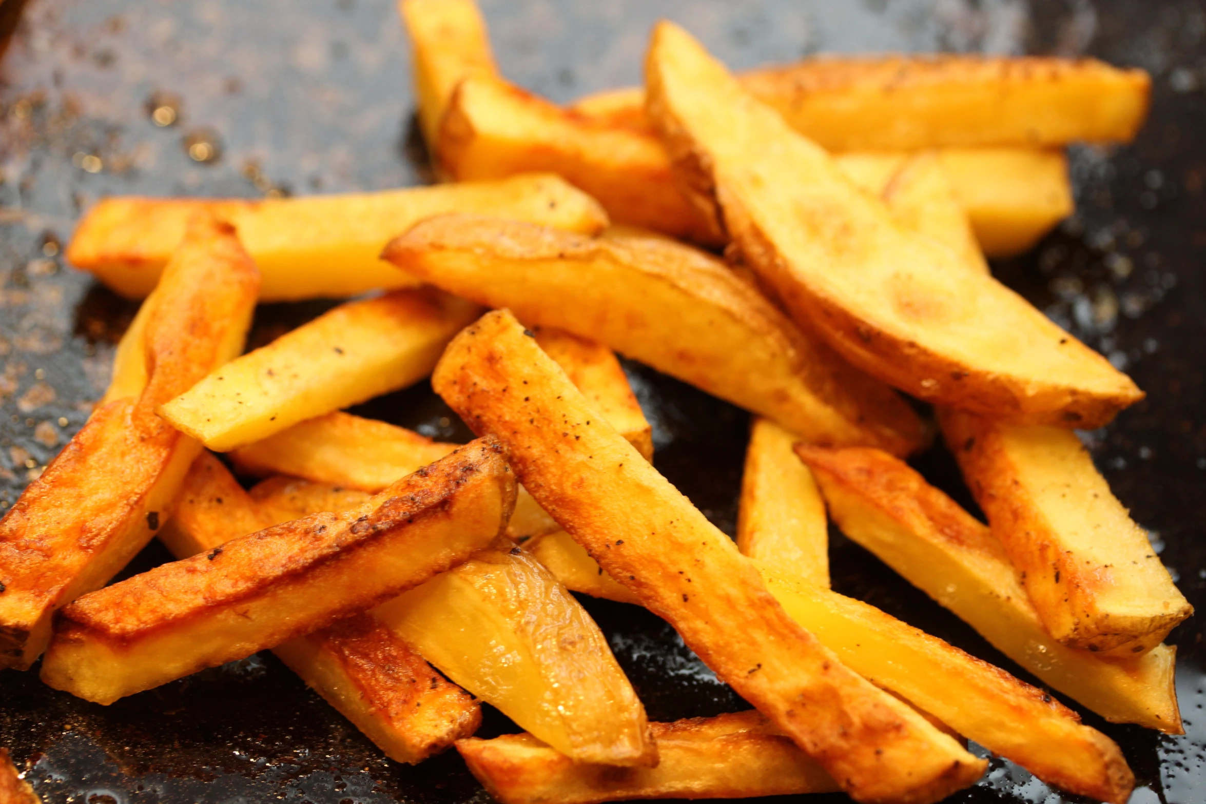 this is a pile of cooked fries with some oil on the ground