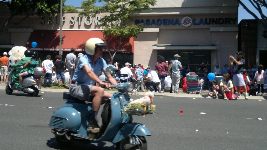 a man on a blue moped next to a crowd