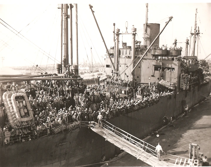 black and white pograph of large group of people near a large ship