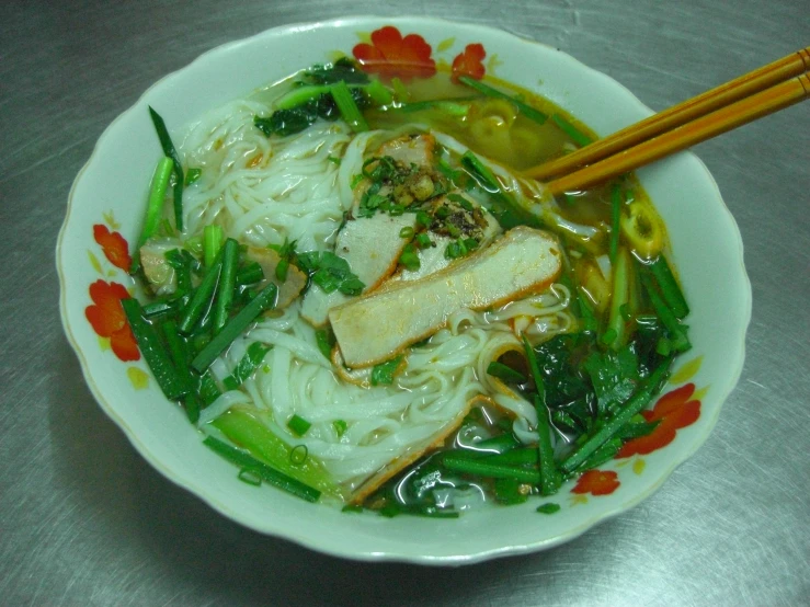 bowl filled with food, and chop sticks on top