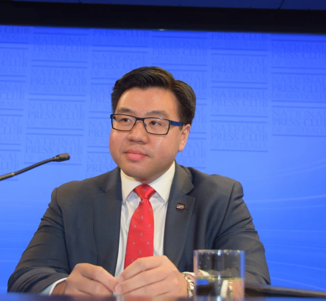 a man in a suit sitting in front of a microphone