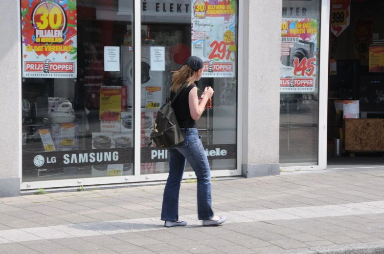 the woman is walking through the busy sidewalk by the stores
