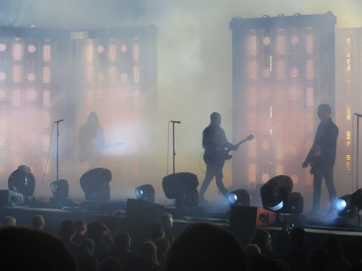 there are three guitar players on the stage