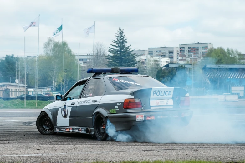 a police car driving with smoke from the rear wheel